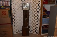 Full view of the Brentwood grandmother clock, showing its dark wood finish, tall structure, and rectangular pendulum window.