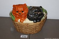 Front view of cookie jar showing orange and black cats lounging on a basket-shaped jar