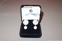 Photo of pearl drop earrings with rhinestone clusters in black velvet box, front view