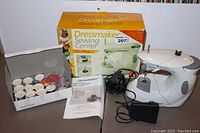 Full view of Dressmaker Mini Sewing Machine, foot pedal, power cord, instruction manual, and original box.