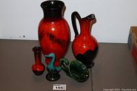 Five pottery pieces displayed on a table: large vase, pitcher, small vase, duck figurine, and green decorative piece