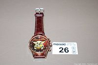 Front perspective photo of the men's watch displaying Grogu and Packers logo on the dial, brown leather strap visible