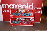 Two Kellogg's 100th Anniversary advertising die-cast car sets in original boxes, displayed on table with signage in background.