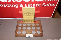 Wooden board displaying 15 coins with a booklet behind it, titled 'The Prime Ministers of Canada.' The coins show signs of tarnishing and dirt, suggesting the set requires cleaning.