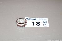 Silver ring stamped 925 with three rows of stones: middle row of red rhinestones and outer rows of clear rhinestones, shown lying flat beside auction tag.