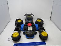 Full view of Batman transformer toy car on white background with ruler for scale.