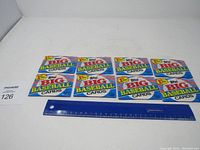 Eight unopened Topps Big Baseball Cards packs arranged side by side on white surface with ruler for scale.