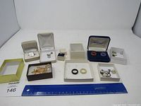 Full view of all jewelry items in their respective boxes with ruler for scale