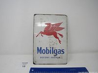 Front view of rectangular metal sign showing white background with red winged Pegasus logo and blue 'Mobilgas' text with 'SOCONY-VACUUM' smaller text below.