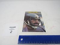 Front view of vintage large-sized Topps football card showing Franco Harris in Pittsburgh Steelers helmet with ruler for size indication.