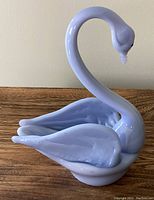Side angle view of the light blue glass swan showing the curved neck and folded wings.