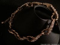 Gold-tone bracelet with swirled links set with crystals captured on black background to show detail.