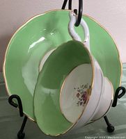 Front angle showing inside of teacup with floral design and green exterior, and saucer in background