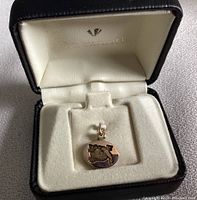 Charm in original jewelry box with cream velvet lining and black exterior.