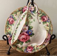 Overview of the corset style teacup resting inside saucer showing floral pattern and gilded edges