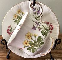Front angle showing teacup resting in saucer, highlighting floral designs and gold trim.