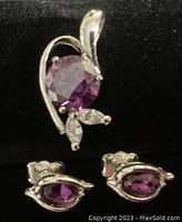 Close-up of the pendant and one earring showing round and oval purple rhinestones with clear rhinestone accents in silver-colored setting.