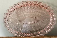 Top view of the pink depression glass oval platter showing its scalloped edge and Buttons and Bows pattern.