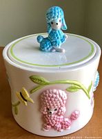 Front view showing blue poodle lid knob and pink poodle on jar body