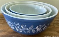 Set of three nested vintage Pyrex bowls with distinctive blue and white floral bird pattern