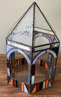 Full view of stained glass terrarium showing colored glass panels with arch design and pointed pyramidal top.
