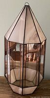 Front view of peach stained glass terrarium with geometric elongated shape and pointed top.