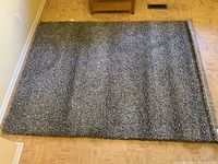 Full top view of grey shag area rug laid on hardwood floor, showing texture and size.