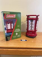Coleman LED Quad Lantern in original box next to out of box lantern on a wooden surface