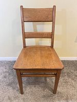 Full front view of the vintage solid oak chair showing the square seat and backrest with two slats.