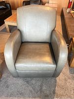 Front view of the grey leather chair showing armrests and seat cushion.