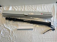 Monopod with Manfrotto branding shown with original box and instruction manual on fabric surface.