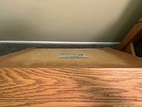 Top surface of nightstand showing wood grain with attached label