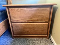 Front view of solid oak nightstand showing two drawers with wood grain finish.