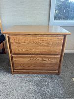 Front view of the solid oak nightstand showing two drawers with recessed handles and warm wood grain finish.