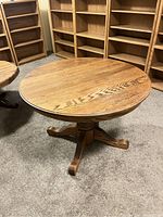 Full view of round oak dining table with pedestal base