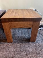 Front and side view of the vintage solid oak side table displaying its thick square legs and sturdy construction.