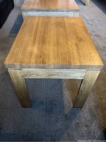 Front view of the vintage solid oak side table showing square top and four sturdy legs on carpeted floor.