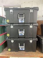 Three black Sterilite storage bins stacked on shelf