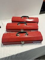 Three stacked red metal tool boxes with black handles and metal latches, all branded Mastercraft.