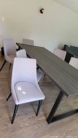 Six light gray upholstered dining chairs arranged around a dining table, showing the overall set and style.