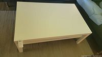 Top view showing flat rectangular white wooden surface of coffee table with minor surface signs.