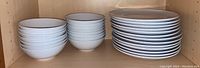Three stacks of white IKEA dishware: large shallow plates on the right, medium bowls on the left, and smaller bowls in the middle.