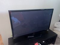 Front view of the LG 42 inch TV on stand with remote control placed on the base of the TV.