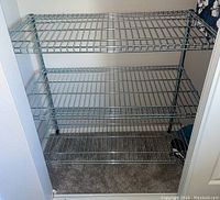 View of one metal wire shelving unit with three wire shelves in a small closet space.