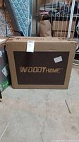 Brown cardboard box with Woody Home branding on the front, indicating the make of the item inside.