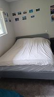 Assembled queen bed with headboard and bedding against wall