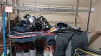 Fisher RX4 skis with bindings, ski boots, clothing including coat and pants visible on metal shelf.