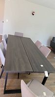 Full view of rectangular wooden table with dark wood finish top and black metal legs, surrounded by chairs.