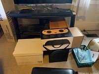 Overview of shelf with DVD player, boxed Bob Marley speaker, subwoofer, lap trays and crate