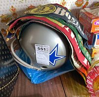 Dallas Cowboys helmet partially covered by vintage pennants on a wooden surface with patterned wallpaper background.